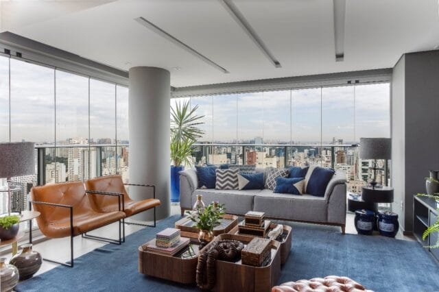 Na área social do duplex, o fechamento de vidro da sala de estar faz da paisagem cosmopolita uma cena viva a ser apreciada